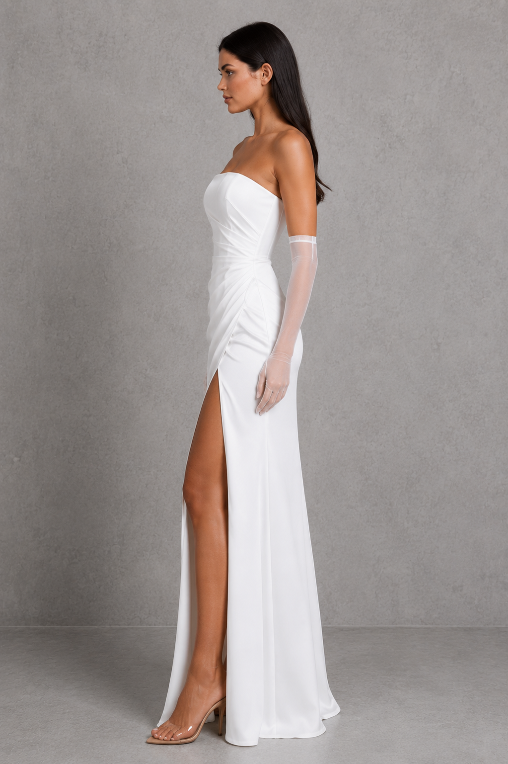 Woman wearing a white strapless gown with a high slit on a gray background