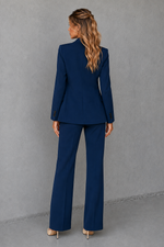 Woman wearing a blue suit standing against a gray background
