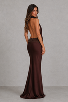 Woman wearing a brown evening gown with an open back against a gray background