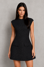Woman wearing a black sleeveless dress against a gray background