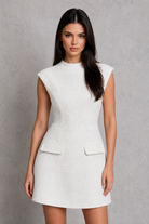 Woman wearing a white sleeveless dress against a gray background
