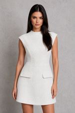Woman wearing a white sleeveless dress against a gray background