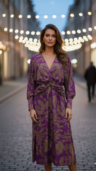 Woman in a purple dress standing on a street with blurred lights in the background