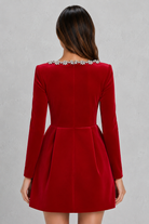 Red dress with long sleeves and embellished neckline on a gray background