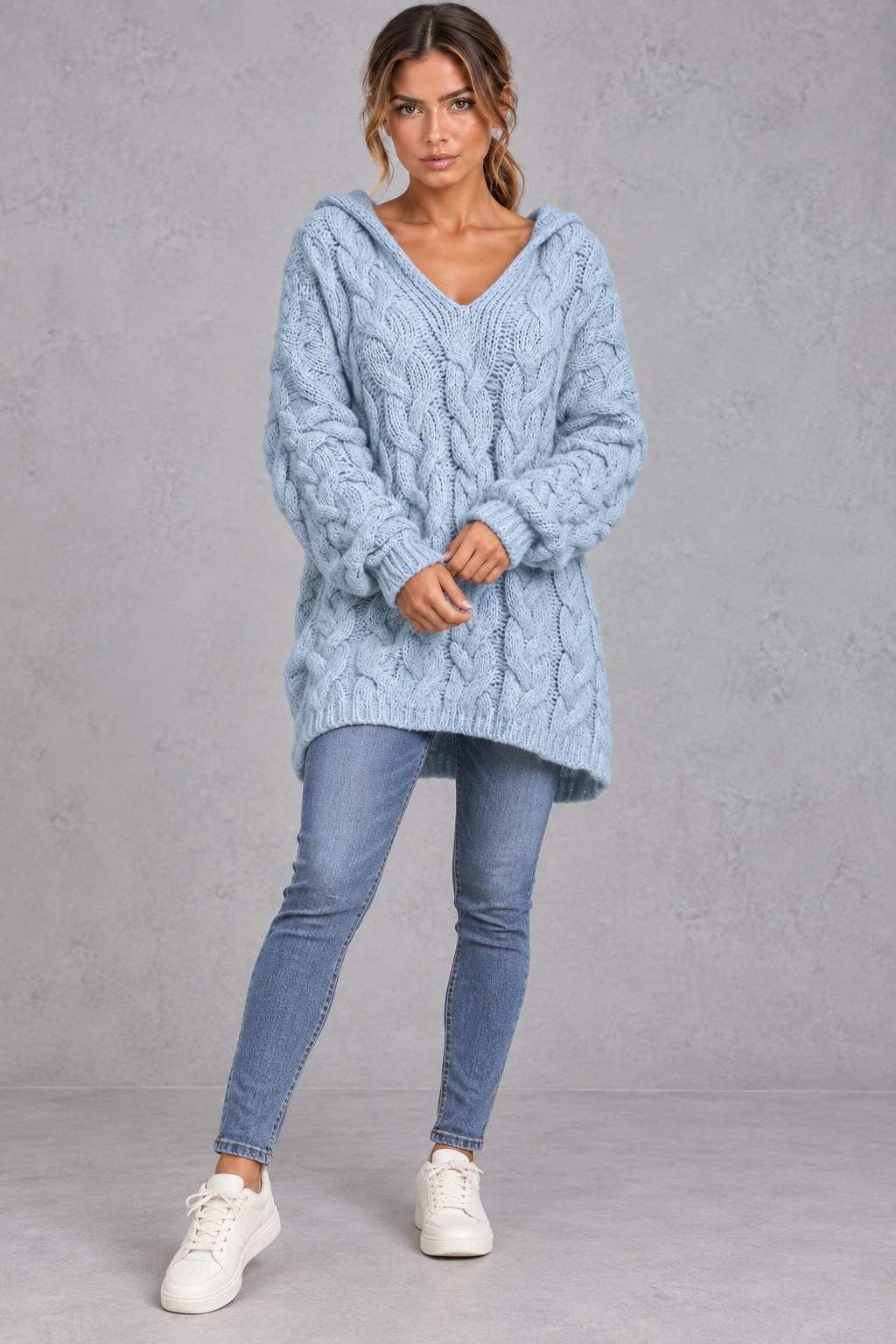 Women's light blue chunky cable knit hooded jumper styled with skinny jeans – full-length front view