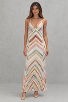 Woman wearing a colorful zigzag patterned dress against a gray background