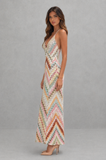 Woman wearing a colorful zigzag patterned dress against a gray background