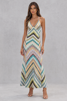 Woman wearing a colorful zigzag patterned dress against a gray background