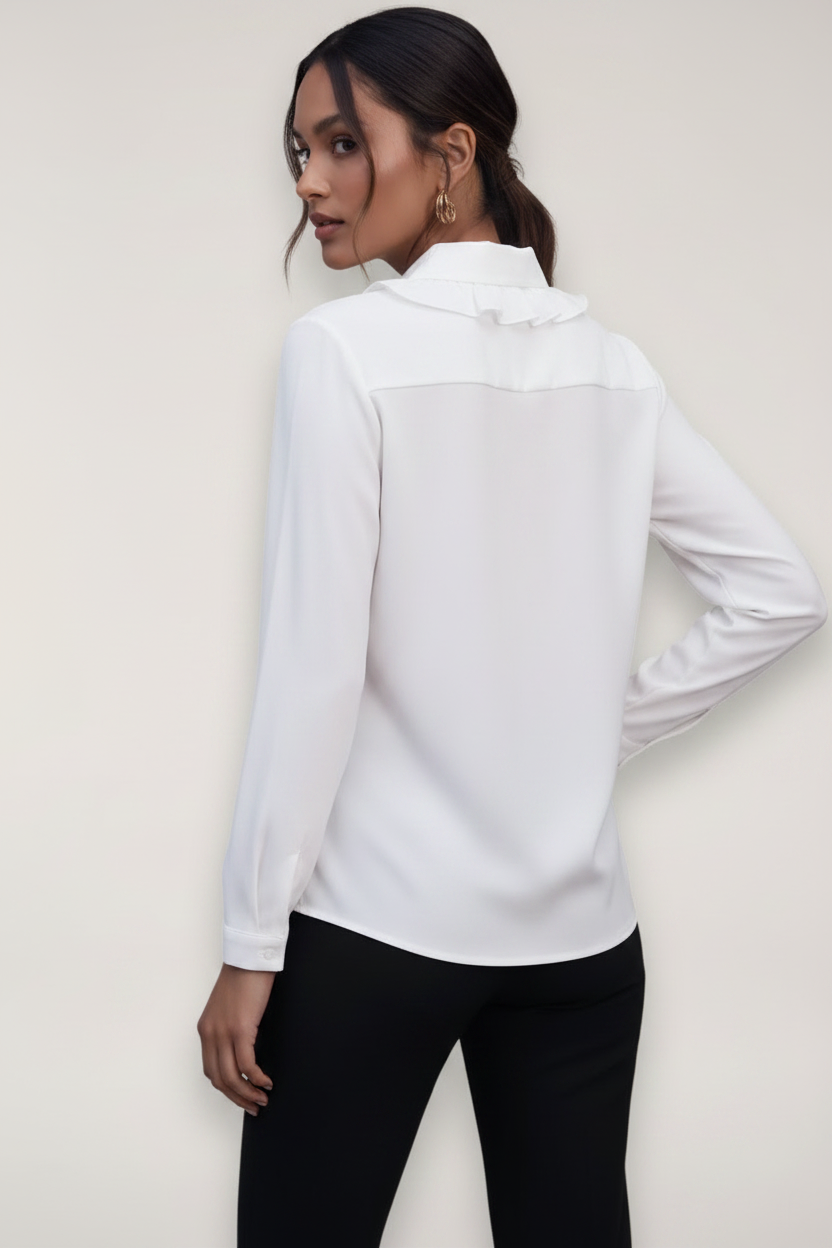Person wearing a white blouse with long sleeves against a plain background