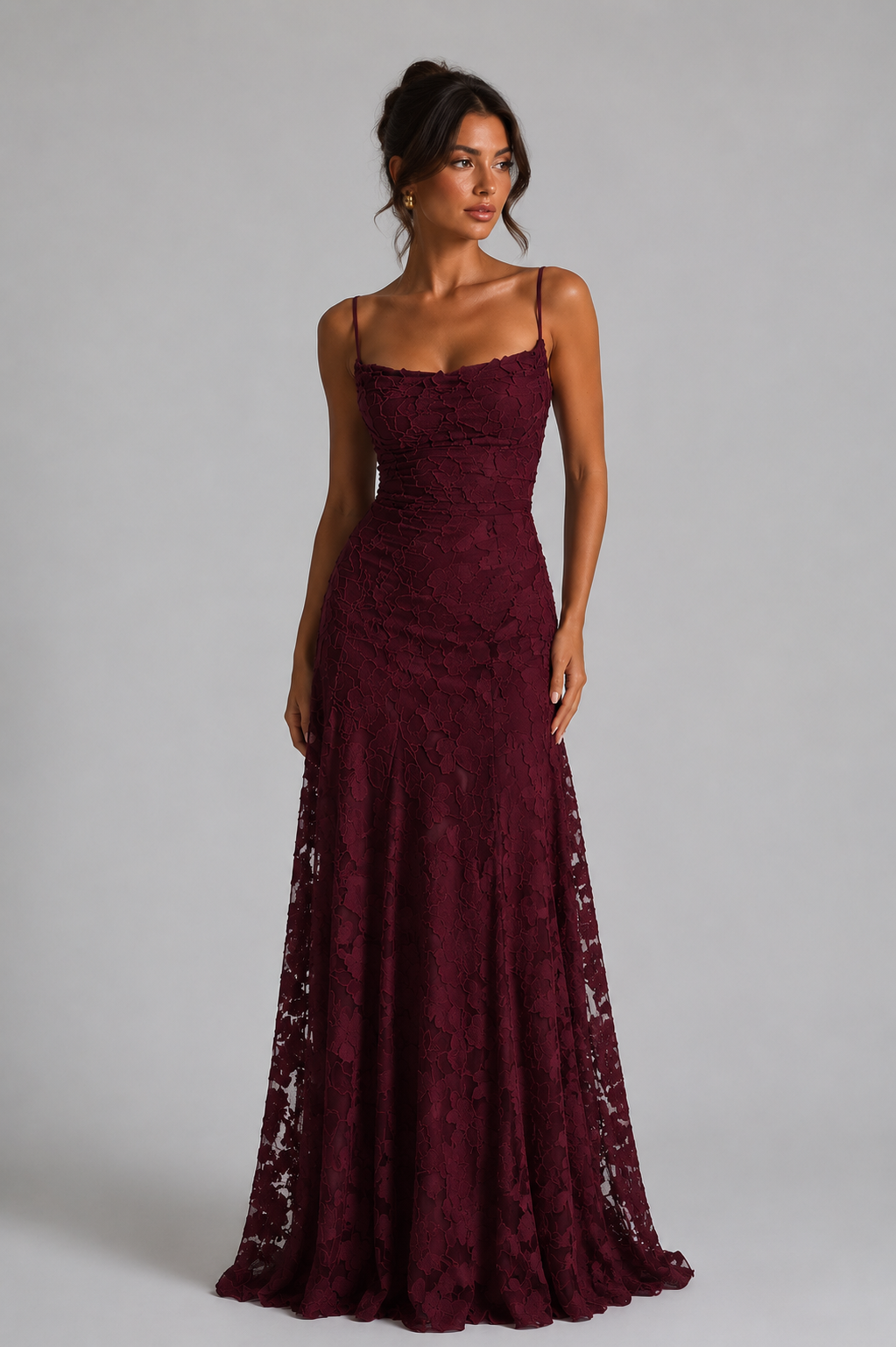 Woman wearing a burgundy lace evening gown against a gray background