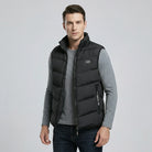 Man wearing a black puffer vest over a gray shirt on a light gray background2