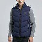 Man wearing a dark blue puffer vest over a gray long-sleeve shirt on a light gray background