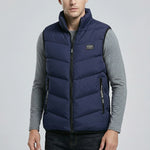 Man wearing a dark blue puffer vest over a gray long-sleeve shirt on a light gray background