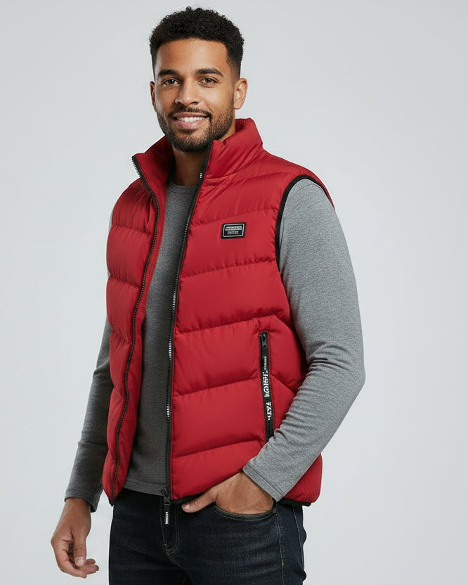 Man wearing a red puffer vest over a gray shirt on a light gray background
