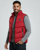 Man wearing a red puffer vest over a gray shirt on a light gray background