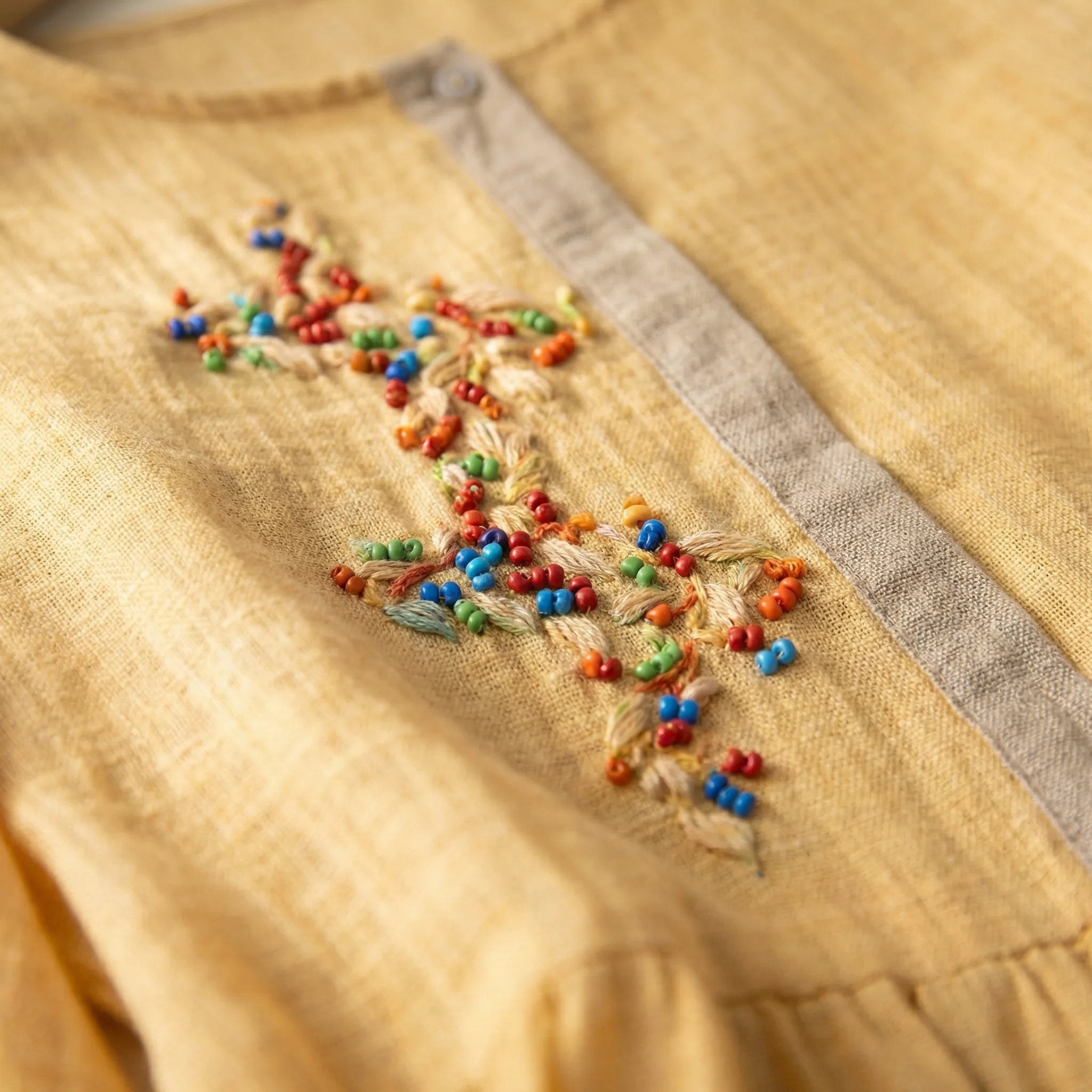 Close-up of a yellow fabric with colorful bead embroidery