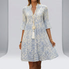 Woman wearing a blue and white patterned dress with a plain3 background