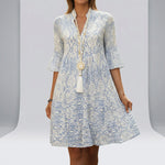 Woman wearing a blue and white patterned dress with a plain3 background