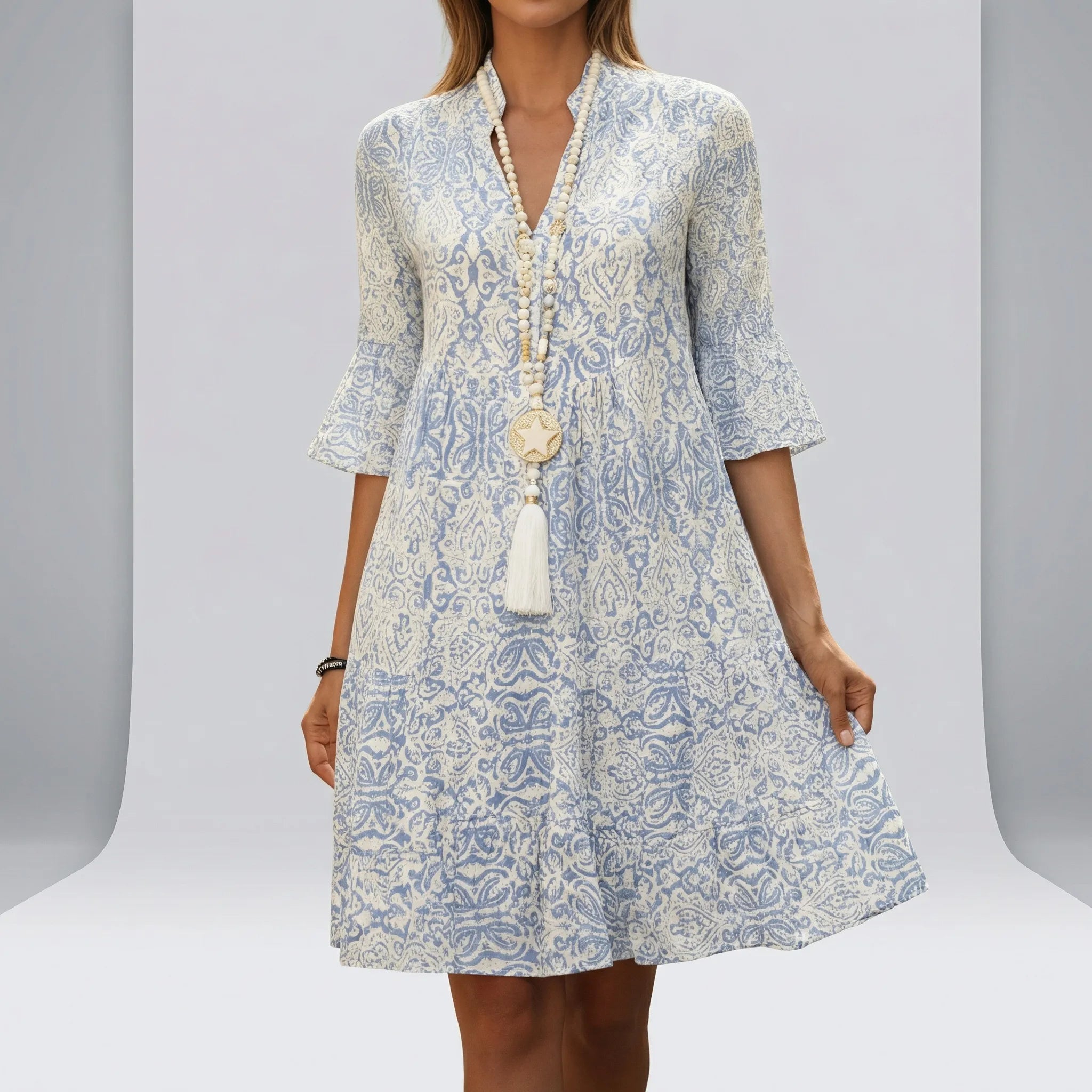 Woman wearing a blue and white patterned dress with a plain3 background