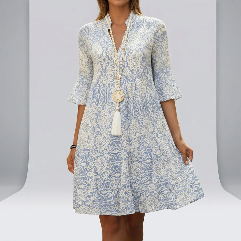 Woman wearing a blue and white patterned dress with a plain3 background