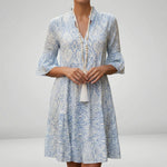 Woman wearing a blue and white patterned dress with a plain background4