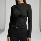 Person wearing a black long-sleeve top and black pants on a light gray background