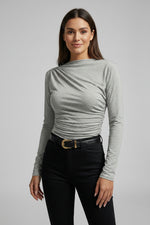 Person wearing a dark gray long-sleeve top and black pants on a plain1 background