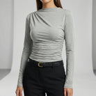 Person wearing a darj gray long-sleeve top and black pants on a light gray background3