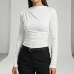 Person wearing a white long-sleeve top and black pants on a light gray background