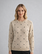 Woman wearing a beige sweater with black polka dots against a gray background