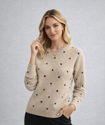 Woman wearing a beige sweater with black polka dots on a gray background