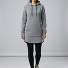 Person wearing a gray hoodie and black leggings on a plain background4