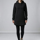Person wearing a black hoodie and leggings on a plain background