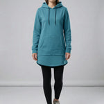 Person wearing a teal hoodie and black leggings on a plain background