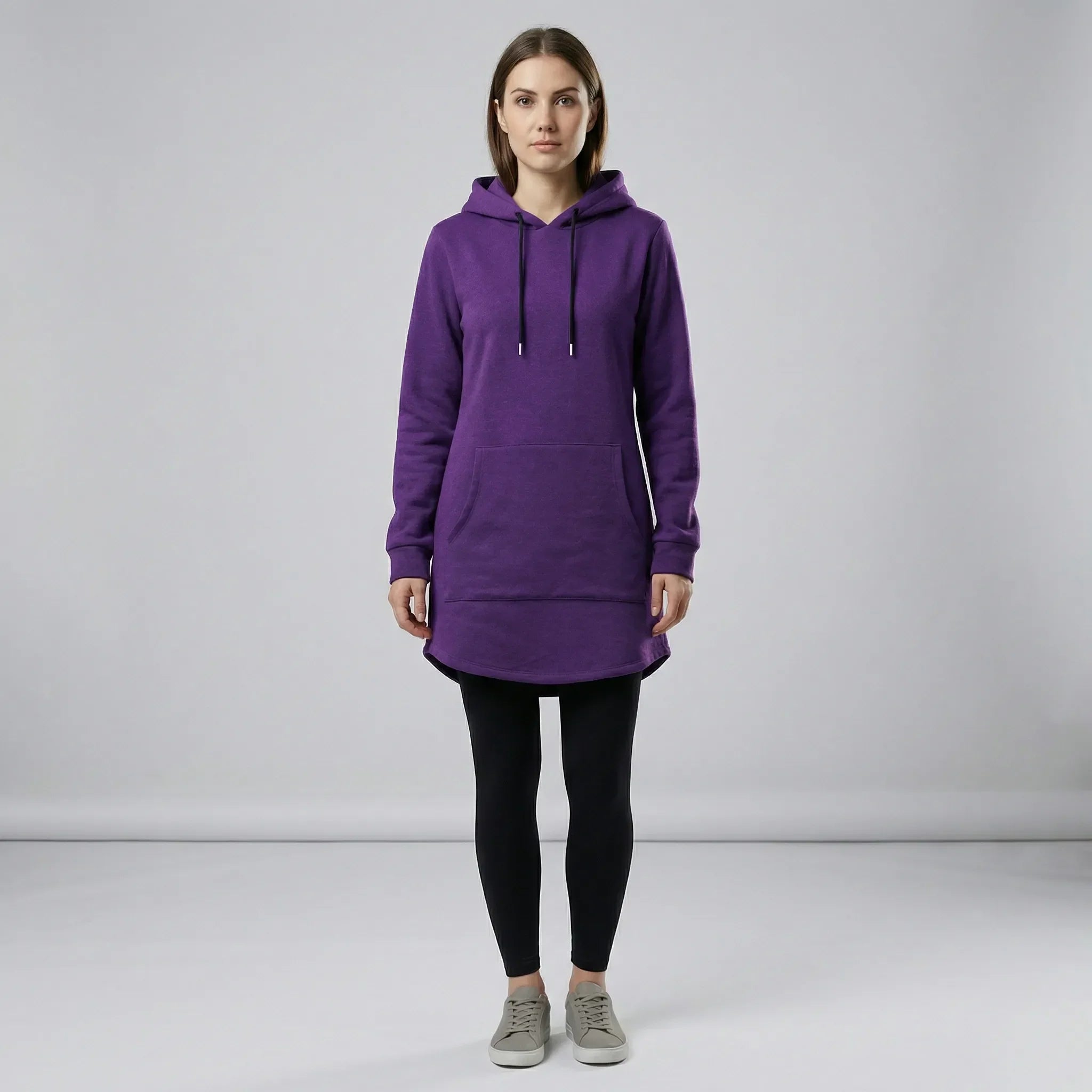 Person wearing a purple hoodie and black leggings on a gray background