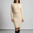 Woman wearing a beige ribbed dress with long sleeves against a plain background2