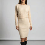 Woman wearing a beige ribbed dress with long sleeves against a plain background2