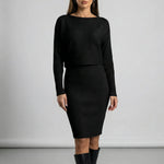 Woman wearing a black ribbed dress against a plain background