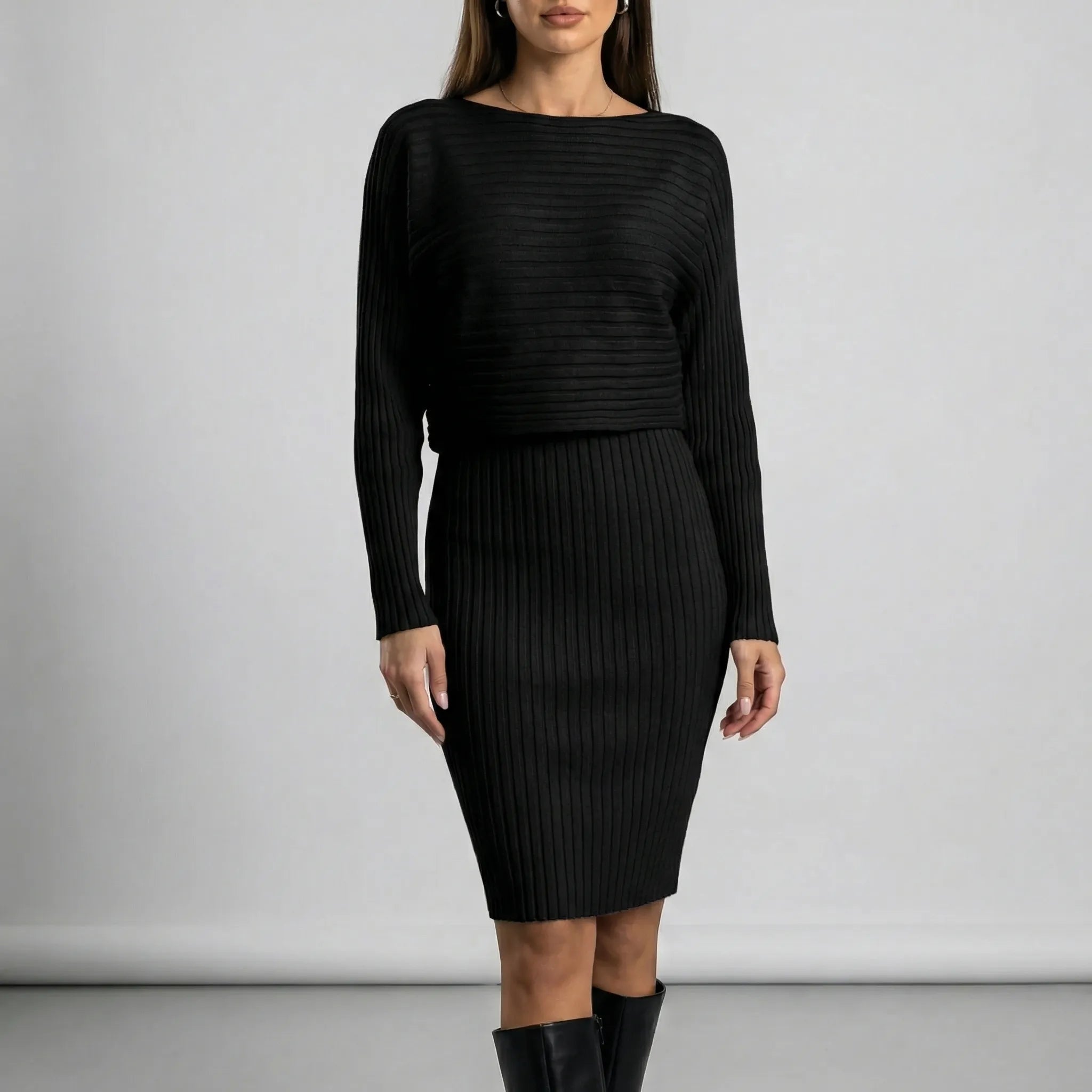 Woman wearing a black ribbed dress against a plain background
