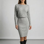 Woman wearing a grey ribbed dress with long sleeves against a plain background