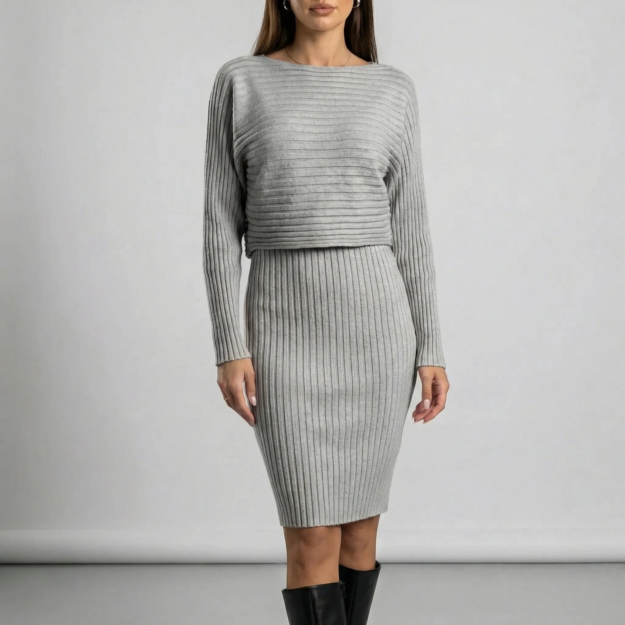 Woman wearing a grey ribbed dress with long sleeves against a plain background