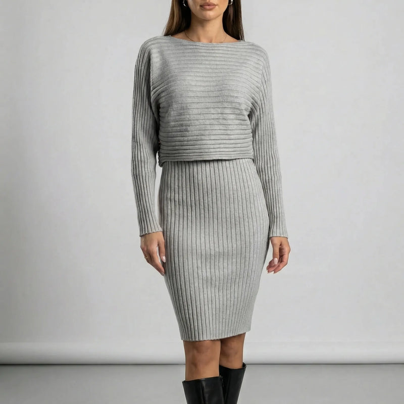 Woman wearing a grey ribbed dress with long sleeves against a plain background