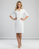 Woman wearing a white dress with a subtle pattern on a plain background