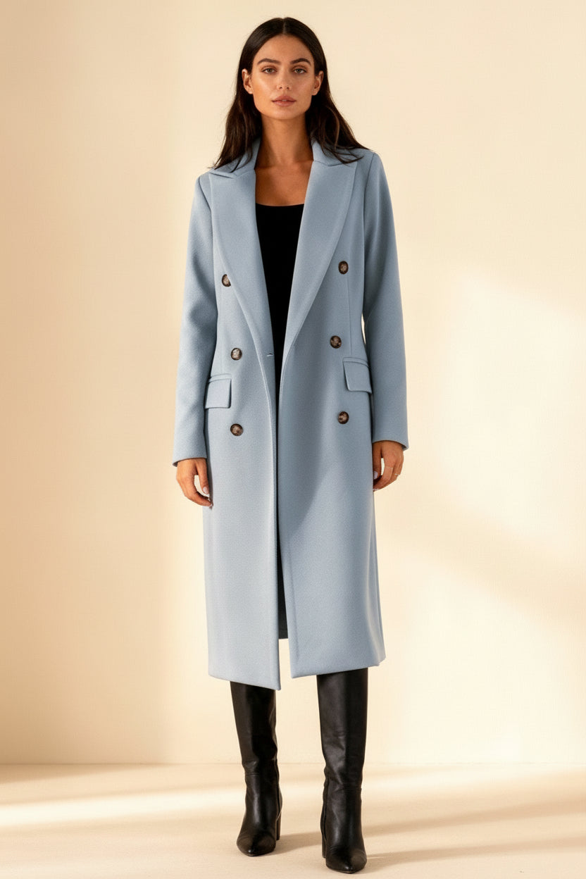 Woman wearing a light blue coat with dark buttons on a beige background