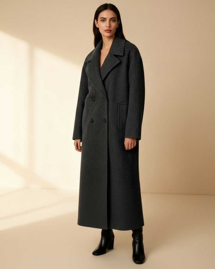 Woman wearing a long dark coat against a beige background