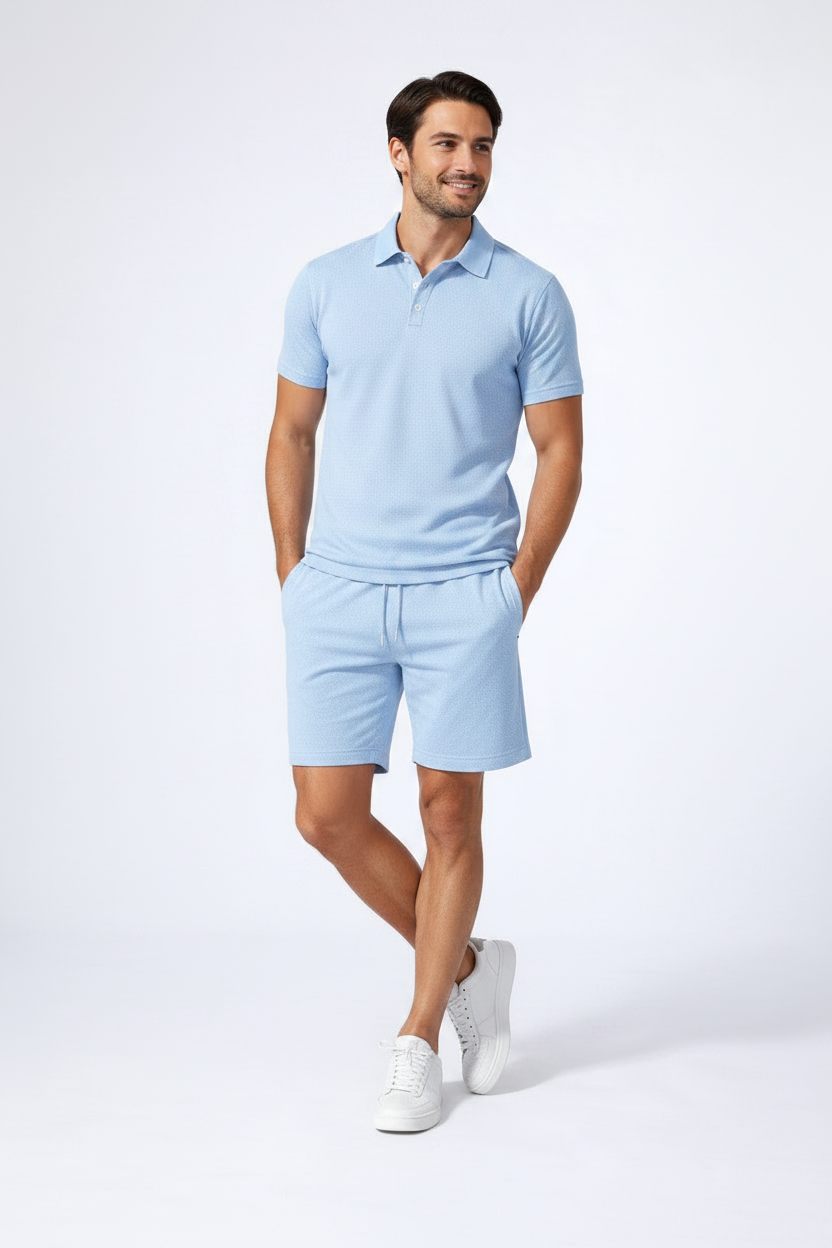 Man wearing a light blue polo shirt and shorts with white sneakers on a white background