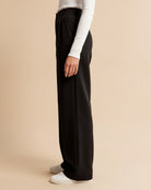 Person wearing black wide-leg pants on a beige background