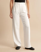 Person wearing white wide-leg pants on a beige background