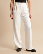 Person wearing white wide-leg pants on a beige background
