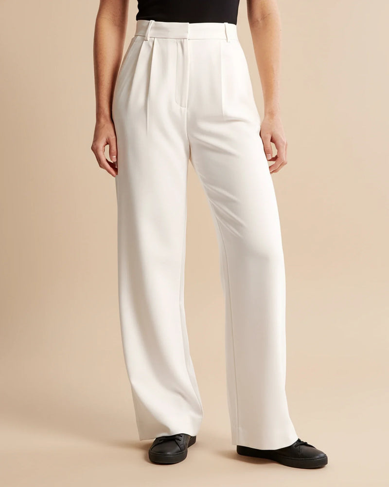 Person wearing white wide-leg pants on a beige background